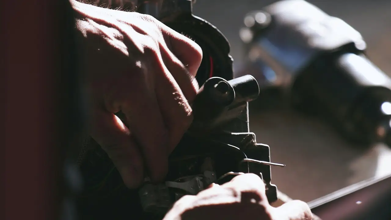 Working on a car engine with a socket wrench, close up on the hands