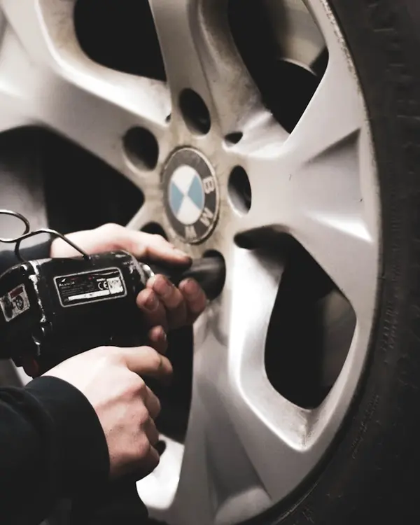 Hands working a tool at an alloy wheel